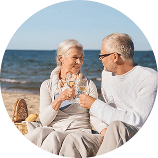 Mature man and woman on the beach toasting with glasses of wine