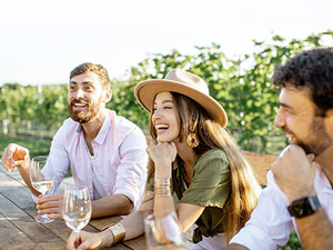 Young women with two young men enjoying a glass of wine outside