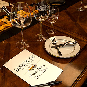 A table set with wine glasses, dinner ware and a menu.