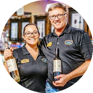 Male and female Lakeridge employees smiling and holding bottles of Lakeridge wine.